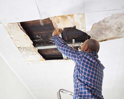 Man removing water damaged roof, Roof Leaks / Tarping by Stallion Restoration