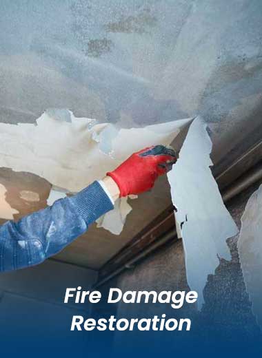 man in blue hoodie and red gloves performing fire damage restoration on a ceiling with Stallion Restoration